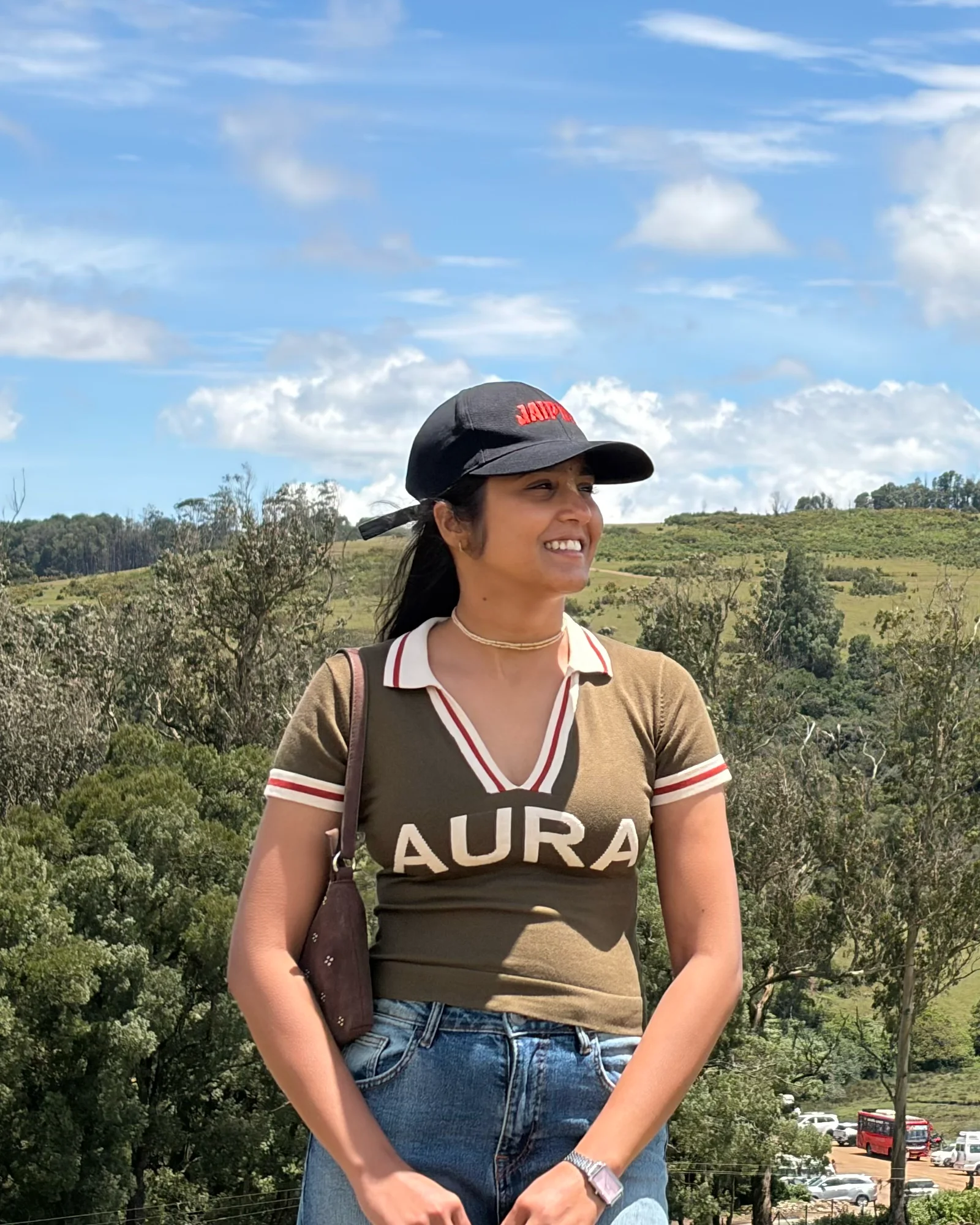Khushi outdoors, with green hills and blue sky behind her